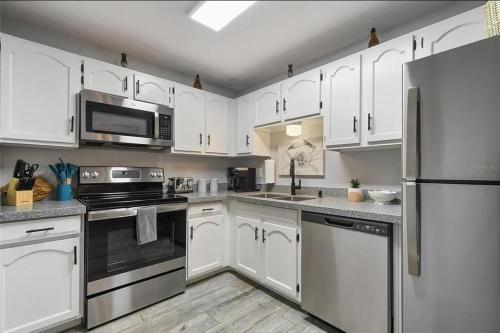 a kitchen with white cabinets and stainless steel appliances at Oceanfront Retreat Private Beach New Smyrna Beach in New Smyrna Beach