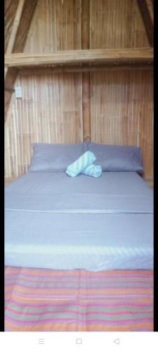 a bed in a wooden room with a blue bedsheet at Bamboo Payag Batangas in Laurel