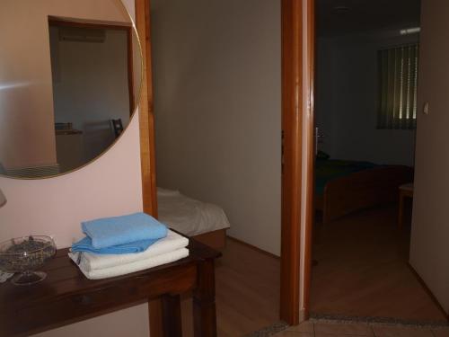 a bathroom with a mirror and a table with towels at Apartments Dumicic in Rab