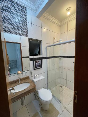 a bathroom with a toilet and a sink and a shower at Flat Centro 302 in Tangara da Serra