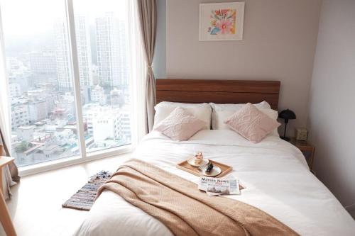 une chambre avec un lit avec un plateau dessus dans l'établissement 광안리해수욕장 30초 베이비 맞춤 풀옵션 패밀리 안심 숙소, à Busan