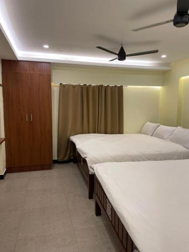 ein Schlafzimmer mit zwei Betten und einem Deckenventilator in der Unterkunft Vishnu VAASAM Serviced Apartment Srirangam in Tiruchchirāppalli