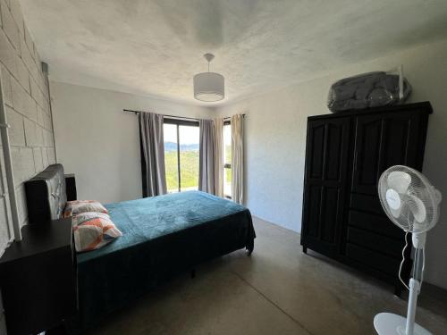 Schlafzimmer mit einem Bett und einem Fenster mit einem Ventilator in der Unterkunft El Descanso in Villa Santa Cruz del Lago