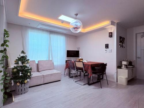 - un salon avec un canapé et une table avec un arbre de Noël dans l'établissement MAYs GO DUCK Newly built Family Stay KSPO IKEA Lotte World, à Séoul