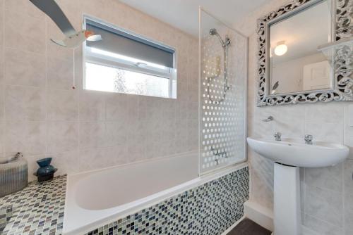 een badkamer met een bad, een wastafel en een spiegel bij Millers Cottage in Broadstairs