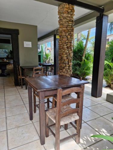 a wooden table and chairs in a restaurant at Pousada das Palmeiras in Garopaba