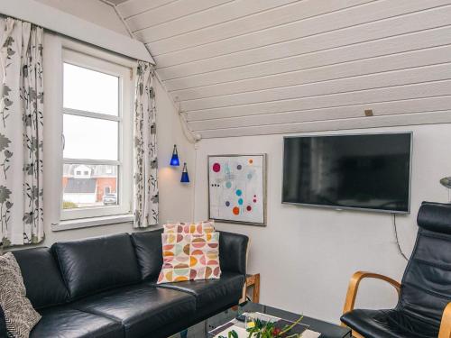 a living room with a black leather couch and a flat screen tv at 4 person holiday home in Rømø in Sønderby