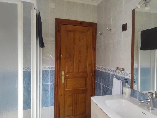 ein Badezimmer mit Waschbecken und Holztür in der Unterkunft El Asturianu in Cangas de Onís