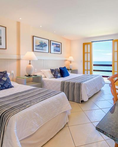 two beds in a room with a view of the ocean at Hotel Vilarejo Praia All Inclusive in Rio das Ostras