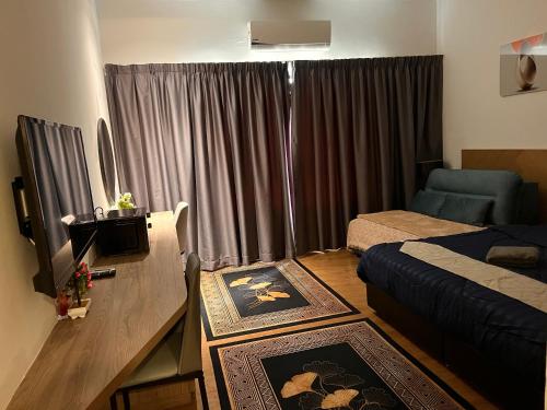 a hotel room with a bed and a desk with a television at AnR Studio Suite Inside H Elite Building in Kota Bharu