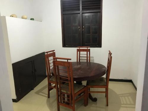 a dining room table with three chairs and a black cabinet at Golden Gate Ways Villa in Hikkaduwa