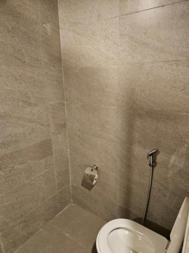 a bathroom with a toilet and a tiled wall at Restful Retreat in Greater Noida