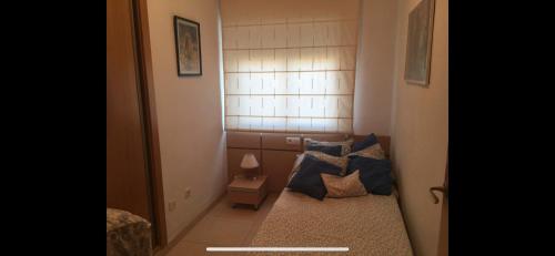 Cette petite chambre comprend un lit avec des oreillers bleus. dans l'établissement Escapada Ideal en Oropesa, à El Borseral