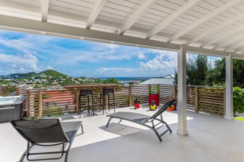 un patio con sillas y una mesa y vistas al océano en NEW Villa 3ch et studio independant Jacuzzi vue mer, en Cul de Sac