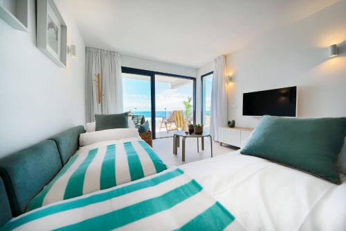 a bedroom with two beds and a couch and a television at Amapola Palms - recién reformado, frente al mar in San Agustin