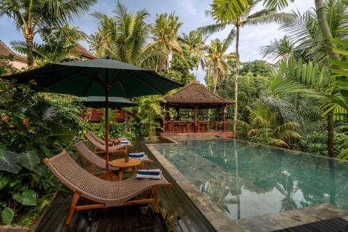 ein Resort mit einem Swimmingpool und Stühlen und einem Sonnenschirm in der Unterkunft Aksmi Suites & Villas in Bedahulu