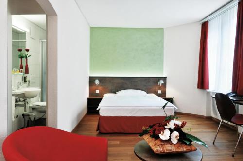 a bedroom with a bed and a red chair at Sorell Hotel Arabelle Bern in Bern