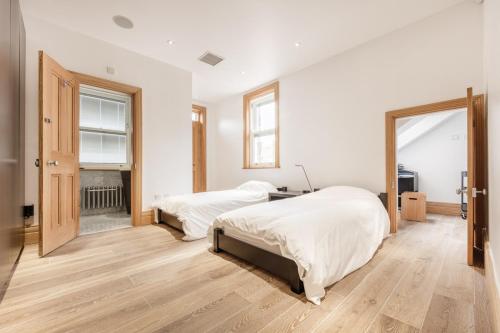 two beds in a bedroom with white walls and wooden floors at Seaview Penthouse 1 in Alnmouth