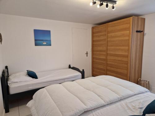 a bedroom with two beds and a large wooden closet at Maison 3 personnes entre lac et forêt in Léry