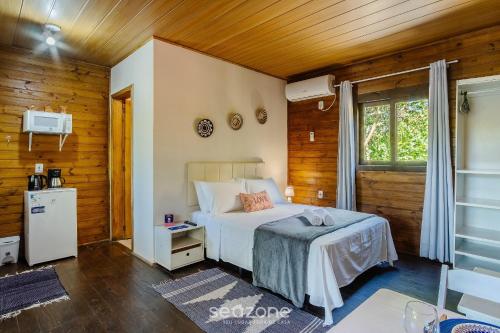 een slaapkamer met een bed in een kamer met houten wanden bij Chalés Elegantes e Completos em Imbituba - REL in Praia do Rosa