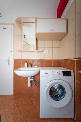 a bathroom with a washing machine and a sink at Apartmani Andreja in Pag