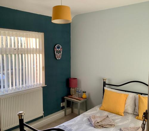 a bedroom with a bed and a blue wall at Lorton Villa with a Log Burner in Saint Helens