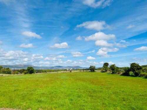 ein Feld von grünem Gras mit blauem Himmel und Wolken in der Unterkunft Brackengarth House in Purdysburn