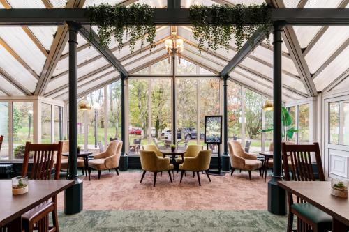 a conservatory with tables and chairs and windows at Mercure Blackburn Dunkenhalgh Hotel & Spa in Blackburn