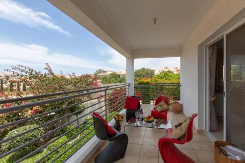 a balcony with red chairs and a table and a view at Spacious sea view apartment in Khlorakas