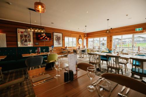 a restaurant with tables and chairs and windows at Landal Ullswater Heights in Great Blencow