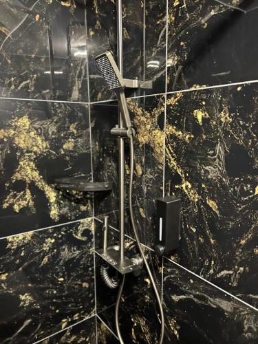 a black tiled bathroom with a blow dryer at Rinn Residence in Iaşi