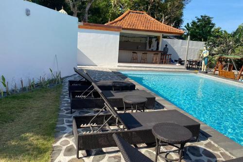 einen Pool mit Tischen und Stühlen neben einem Haus in der Unterkunft Casa Komala Uluwatu in Uluwatu