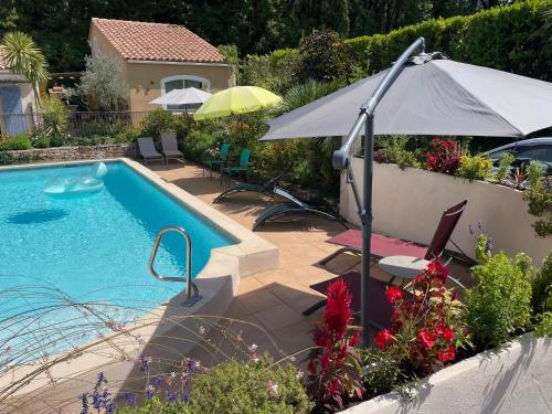 a swimming pool with an umbrella and chairs and a table at Les Hauts d'Eyragues gîte Aigue Marine Meublé classé 4 étoiles in Eyragues