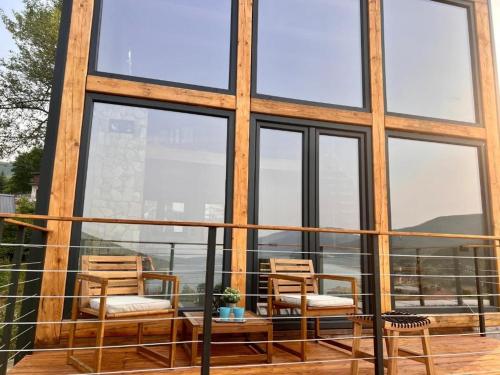 two chairs and a table on a balcony with windows at Mountain Log Cabin in Mavrovo