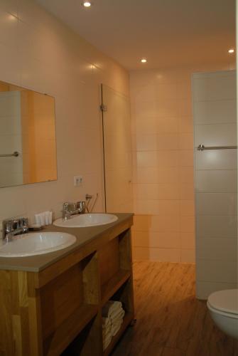 a bathroom with two sinks and a toilet at De Kruishoeve in De Haan