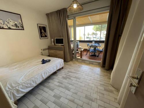 Appt Studio 2 couchages CAP D'AGDE NATURISME في كاب داغد: غرفة نوم بسرير وتلفزيون وطاولة