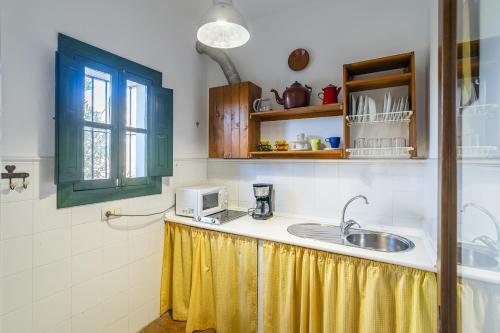 a kitchen with a sink and a microwave at Cubo's Casa Rural Cortijo del Puntal in Teba
