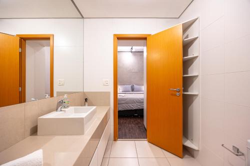 a bathroom with a sink and a mirror and a bed at Premium Modern Studio in Alphaville in Santana de Parnaíba