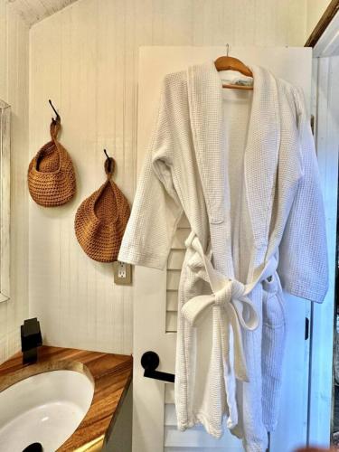 a bathroom with a white robe hanging on a wall at Couples Cottage - Serene Getaway in Citra