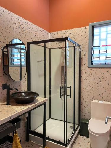 a bathroom with a glass shower and a sink at The Urban Farm House in Accra