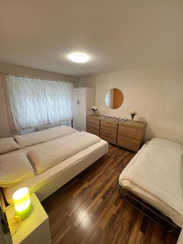 a bedroom with two beds and a table with a lamp at Perle Apartment in Interlaken