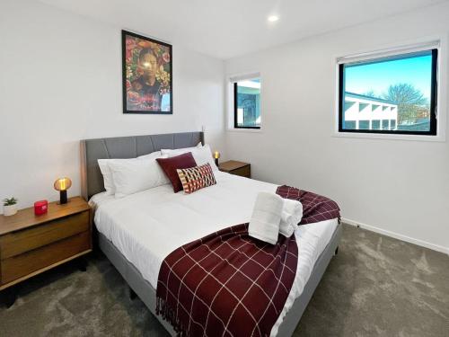 Chic 1-Bedroom Apartment with Balcony in Ferry Rd في Linwood: غرفة نوم بسرير ومكتب ونوافذ