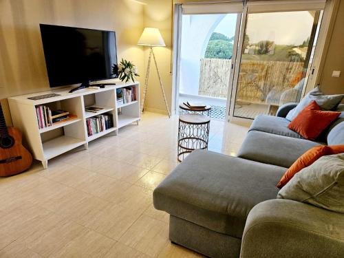 Una sala de estar con un sofá y un televisor de pantalla plana. en Summertime, en Porches