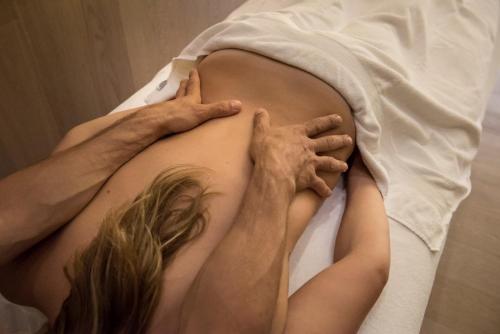 a pregnant woman laying on a bed with her hands on her stomach at Pietre Nere Resort & Spa in Modica