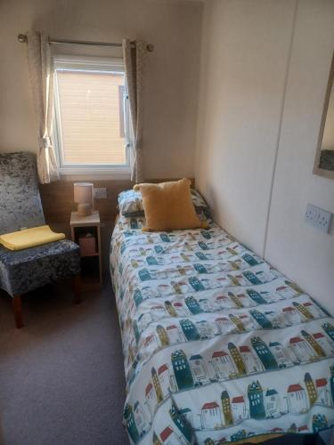 a bedroom with a bed and a chair and a window at 63 The Pastures Tattershall lakes in Lincoln