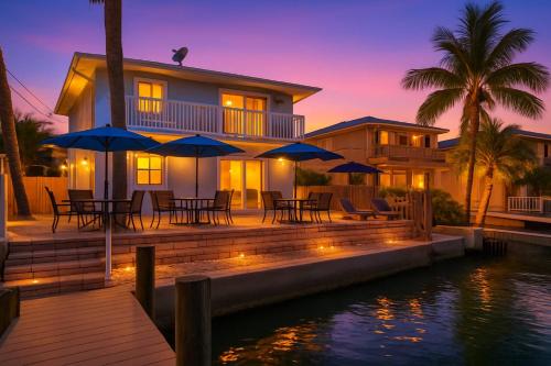 una casa con terraza con mesas y sombrillas en Coastal Breeze Siesta Manatee "C", en Sarasota