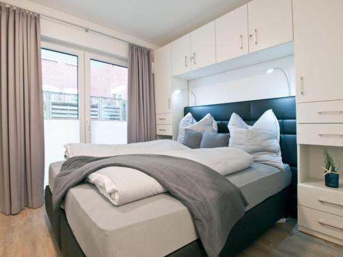 Un dormitorio con una cama grande y una ventana. en Palais Garteneck 4, en Norderney