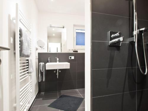 y baño blanco y negro con lavabo y ducha. en Palais Garteneck 4, en Norderney