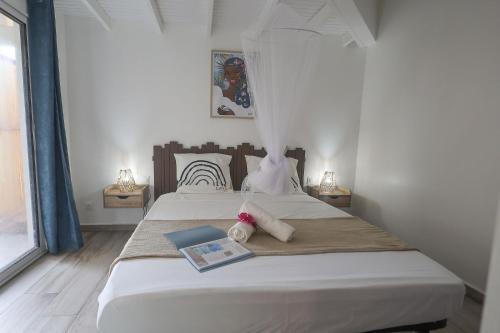a bedroom with a bed with a book on it at L'Escapade Créole in Saint-François