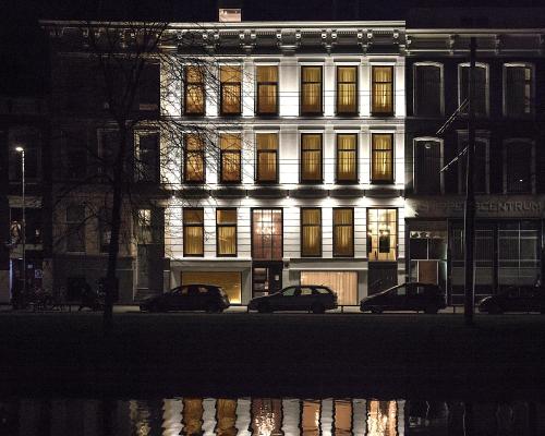 a lit up building with cars parked in front of it at Maurits Apartments & Suites in Rotterdam